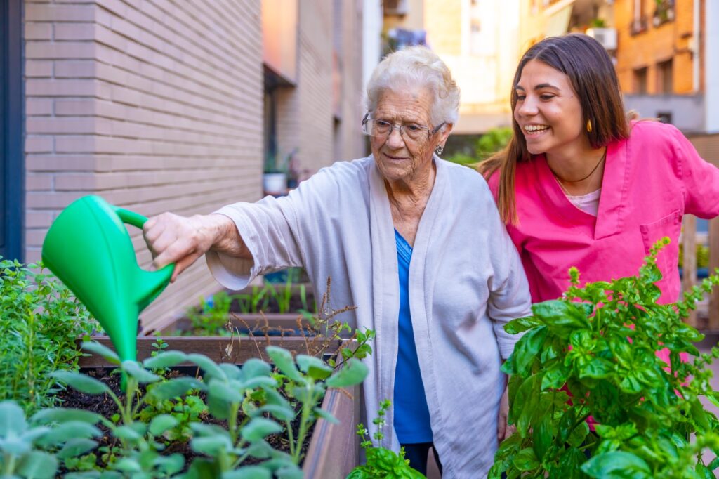 Nurse and elder woman watering herbal plants in a geriatric